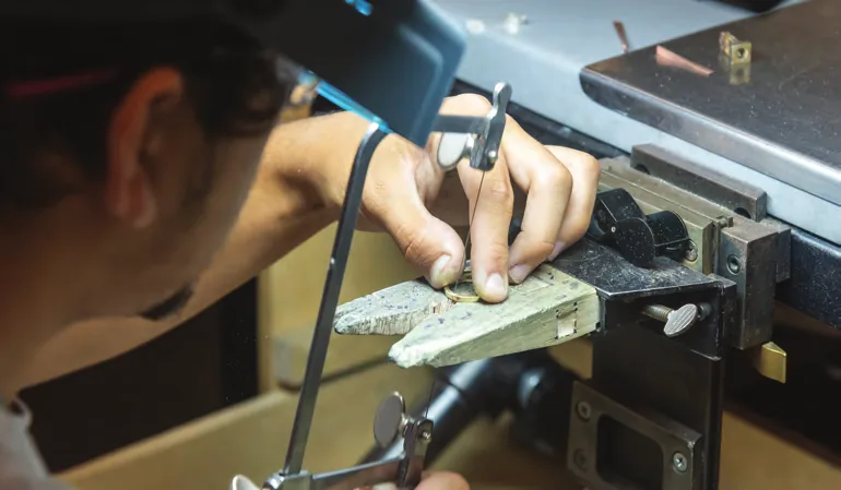 Jeweller working on a piece at the bench with hand tools