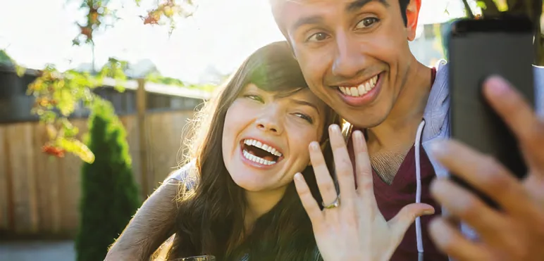 Newly engaged couple celebrating and showing off a diamond engagement ring