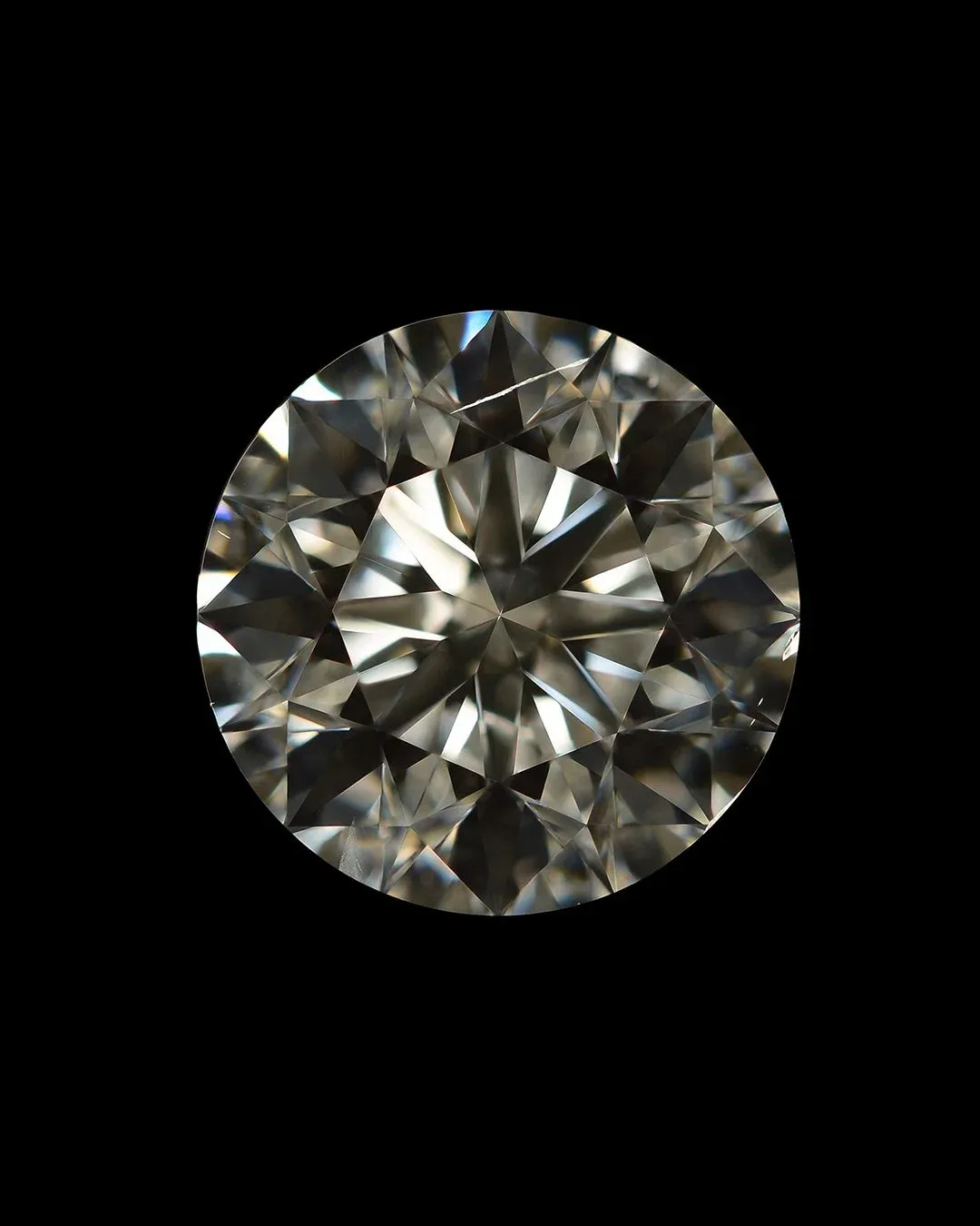 Close-up photo of a round brilliant diamond with visible internal inclusions and birthmarks on a black background.