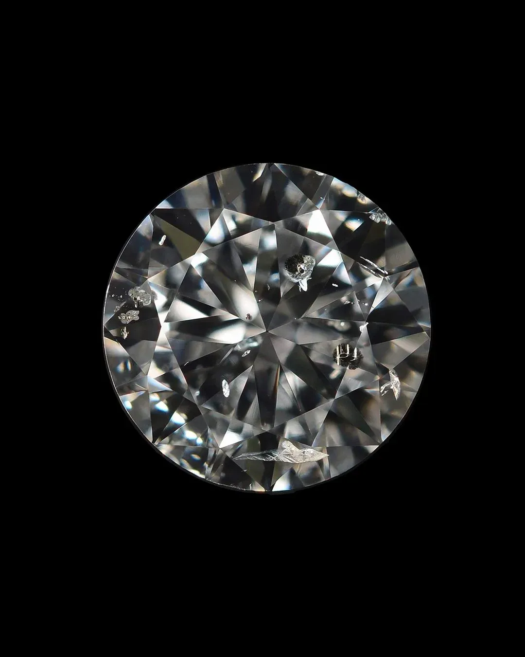 High-resolution close-up of a round brilliant diamond showing visible inclusions that affect clarity.