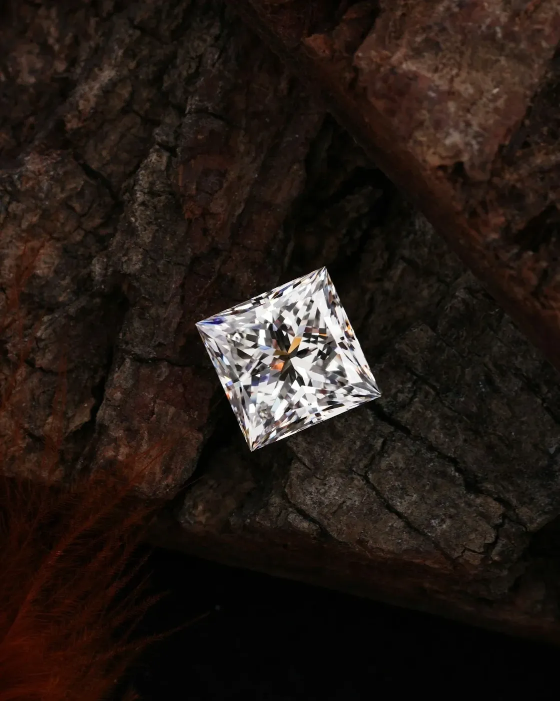 Princess-cut lab-grown diamond placed on rough stone surface showing clarity and sustainable option.