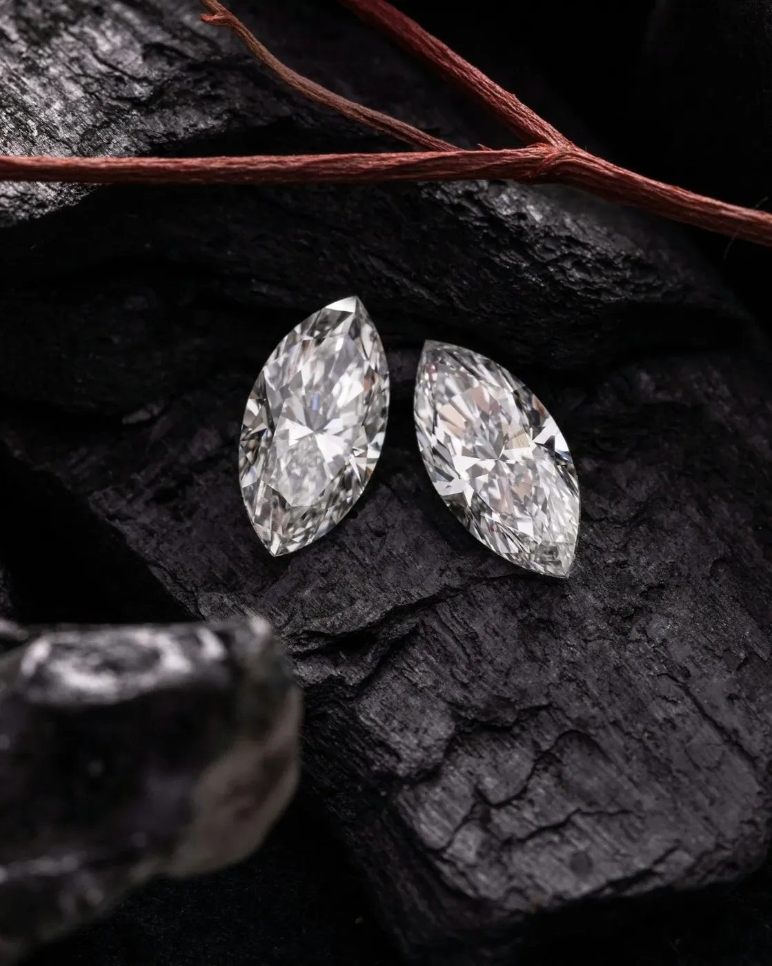 Two marquise-cut diamonds on black stone background symbolizing choice between lab-grown and natural.